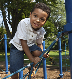 Photo of boy playing on a jungle gym made of ropes