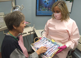 Photo of Dental hygienist Karin Steisel giving a patient a pink toothbrush