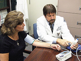 Dr. William White shows a patient how to use a home blood pressure monitor