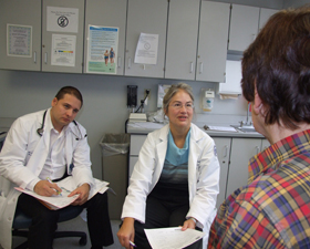 Photo of Dr. Gail Sullivan seeing a patient while Abimbola Aderinto and Dr. Lorand Kristof observe