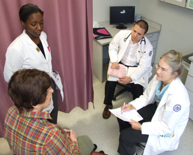 Photo of Dr. Gail Sullivan seeing a patient while Abimbola Aderinto and Dr. Lorand Kristof observe