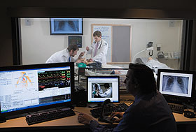 Medical students perform a procedure on SimMan as Dr. Thomas Nowicki, head of medical simulation at UConn, observes from the control room.