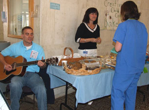 Photo of Nar Scaia playing the guitar by the bake sale table