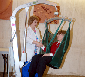 Christine Delgrande of the rheumatology department and Patti Wawzyniecki of the Office of Research Safety demonstrate one of the lifts used to move and transfer patients at John Dempsey Hospital.